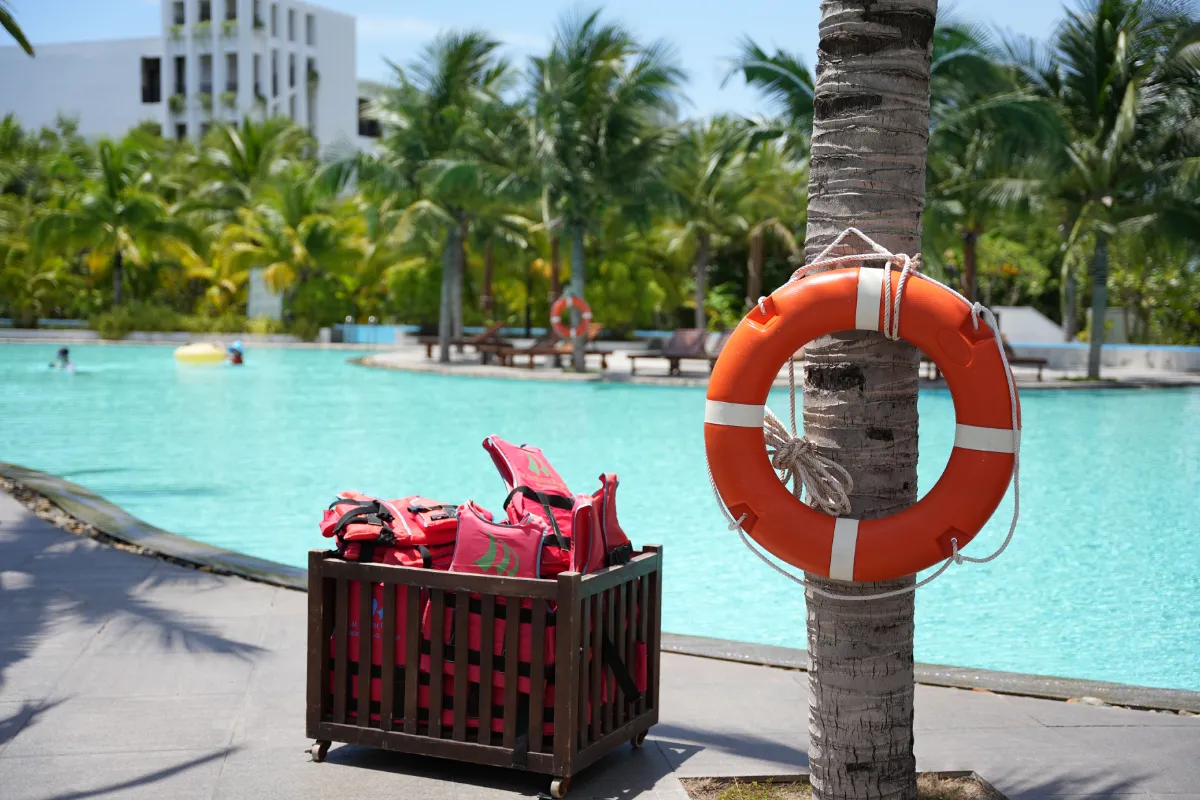 Resort swimming pool with a life ring and life jackets poolside